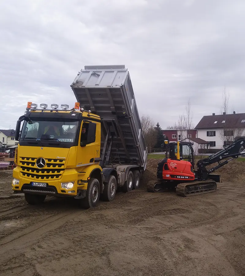 Lkw und Minibagger bei Erdarbeiten auf einer Baustelle