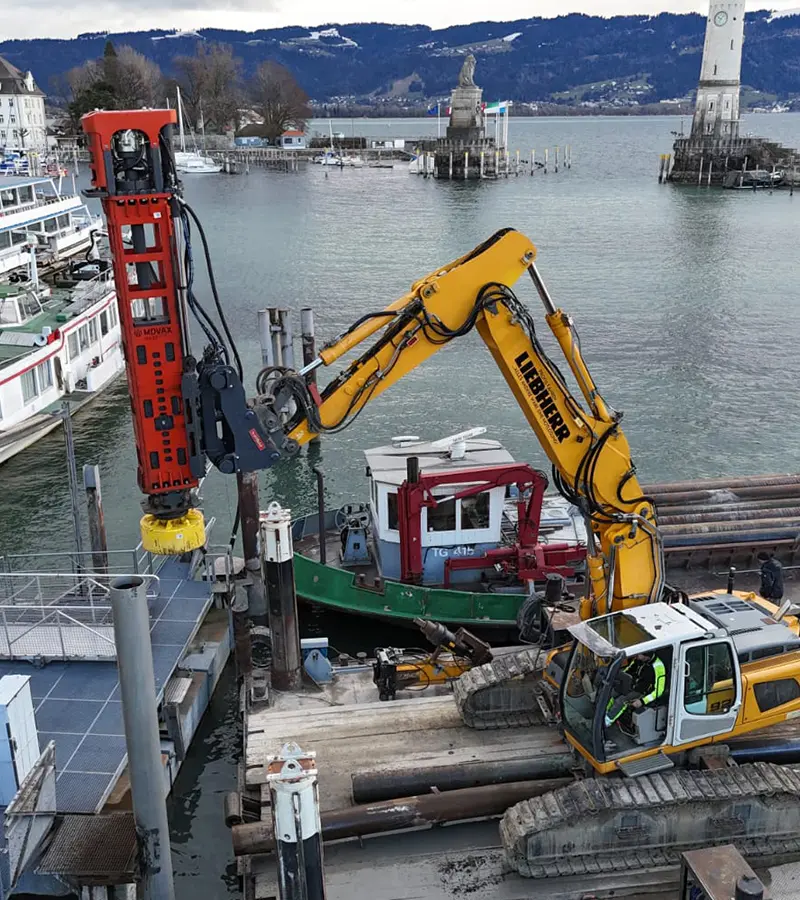 Bagger mit Rammgerät auf einem Ponton im Hafenbereich